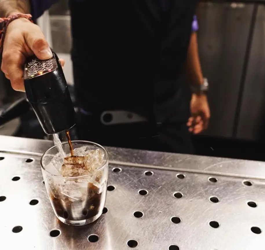 Bartender using Easybar liquor gun system to pour precise cocktail at amusement park bar