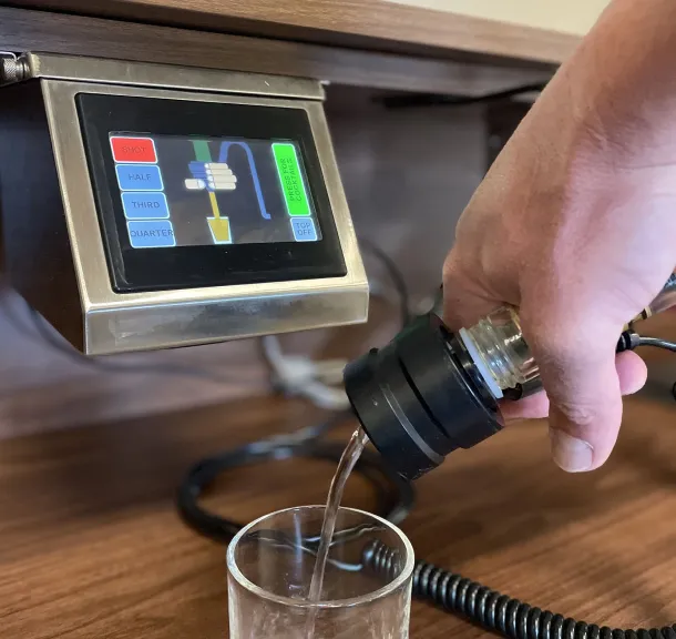 Bartender using touchscreen liquor control pour system to measure spirits into a glass.