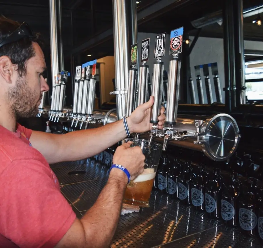 Bar staff operating high-volume draft beer system at theme park beverage outlet