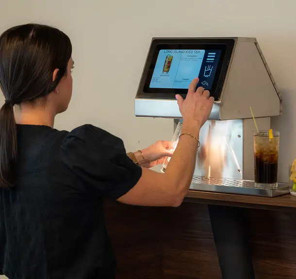 Bartender using an Easybar Easymix Cocktail Station touchscreen to dispense a Long Island Iced Tea into a glass