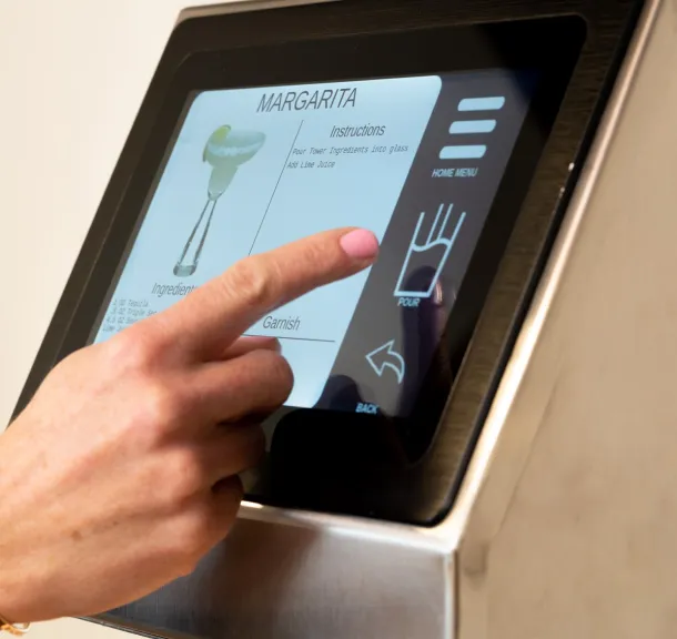 Person selecting a margarita recipe on a commercial cocktail dispenser touchscreen machine.