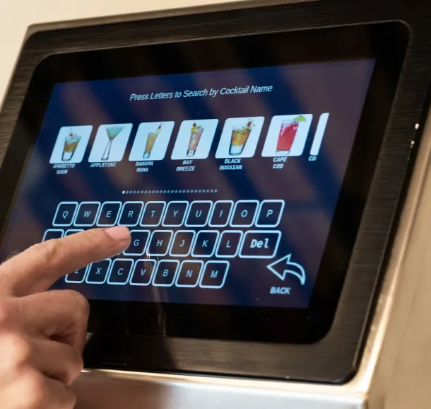 Hand selecting a cocktail on a touchscreen liquor dispenser interface.